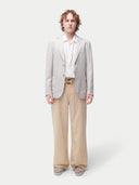 Man wearing a light gray blazer over a white shirt with beige pants on a white background. #color_light-taupe