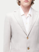 Light gray blazer with a white shirt and gold buttons on a neutral background #color_light-taupe