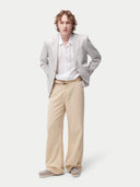 Man wearing a light gray blazer over a white shirt with beige pants on a white background. #color_light-taupe