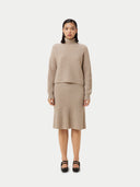 A woman wearing a beige long-sleeved cropped t-neck sweater and a matching skirt. #color_duty-beige