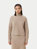 A woman wearing a beige long-sleeved cropped t-neck sweater and a matching skirt. #color_duty-beige