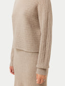 A woman wearing a beige long-sleeved cropped t-neck sweater and a matching skirt. #color_duty-beige