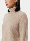 A woman wearing a beige long-sleeved cropped t-neck sweater and a matching skirt. #color_duty-beige