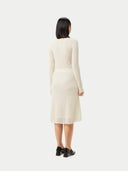 A woman wearing a beige knit cashmere skirt with an elasticated high-waist, paired with a white blouse with a sleeve detail.  #color_off-white