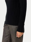 A black ribbed knit mock neck cashmere sweater with long sleeves and ribbed cuffs, displayed flat against a light gray background. #color_black