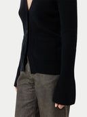 A woman wearing a black cashmere v-neck buttoned cardigan over a cashmere top and shorts. #color_black