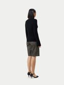 A woman wearing a black cashmere v-neck buttoned cardigan over a cashmere top and shorts. #color_black