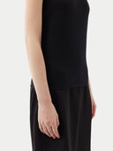 Woman wearing a black one-shoulder cashmere top against a white background #color_black
