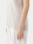 Woman wearing a light pink sleeveless cashmere top and white pants on a white background. #color_pure-white