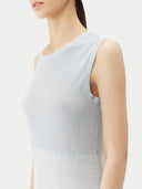 A woman standing in a studio setting, wearing a sleeveless, solid blue cashmere dress with a round neckline. #color_soft-ice