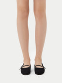 Pair of black flat shoes with a strap on a light gray background #color_black