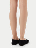 Pair of black flat shoes with a strap on a light gray background #color_black