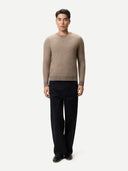 Man wearing a beige cashmere sweater and black pants on a white background. #color_taupe