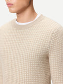 Close-up of a person wearing a textured beige cashmere sweater with a white collar. #color_dusty-beige