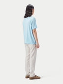 Man wearing a light blue polo shirt and white pants against a plain background #color_forget-blue