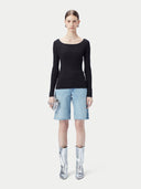 A woman wearing a ribbed cotton silk cashmere blend sweater in black color with a V-neckline and long sleeves, paired with a pair of light blue denim shorts. 
#color_graphite-black