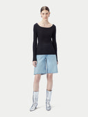 A woman wearing a ribbed cotton silk cashmere blend sweater in black color with a V-neckline and long sleeves, paired with a pair of light blue denim shorts. 
#color_graphite-black