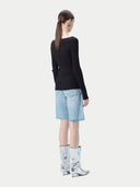 A woman wearing a ribbed cotton silk cashmere blend sweater in black color with a V-neckline and long sleeves, paired with a pair of light blue denim shorts. 
#color_graphite-black