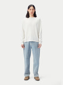 A long-sleeve crewneck knit cashmere sweater in a warm off-white or cream color, displayed flat against a light gray background. #color_pure-white