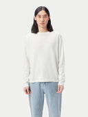 A long-sleeve crewneck knit cashmere sweater in a warm off-white or cream color, displayed flat against a light gray background. #color_pure-white