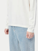 A long-sleeve crewneck knit cashmere sweater in a warm off-white or cream color, displayed flat against a light gray background. #color_pure-white