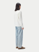 A long-sleeve crewneck knit cashmere sweater in a warm off-white or cream color, displayed flat against a light gray background. #color_pure-white