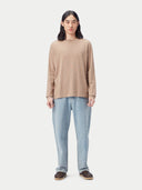 Person wearing a beige cashmere sweater and light blue jeans on a white background #color_taupe-brown