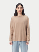 Person wearing a beige cashmere sweater and light blue jeans on a white background #color_taupe-brown
