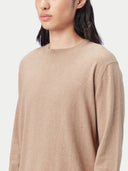 Person wearing a beige cashmere sweater and light blue jeans on a white background #color_taupe-brown