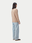 Person wearing a beige cashmere sweater and light blue jeans on a white background #color_taupe-brown