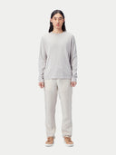 Person wearing a light gray long-sleeve shirt and light-colored pants on a white background #color_warm-light
