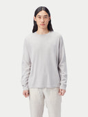 Person wearing a light gray long-sleeve shirt and light-colored pants on a white background #color_warm-light
