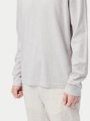 Person wearing a light gray long-sleeve shirt and light-colored pants on a white background #color_warm-light
