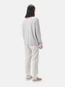 Person wearing a light gray long-sleeve shirt and light-colored pants on a white background #color_warm-light
