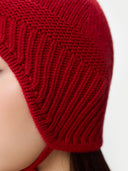 Ultimate Warmth Knit Tie Hat Chili Pepper worn by model, side view on white background #color_warm-red