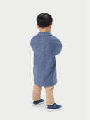 A child wearing a blue cashmere coat with buttons, over a white shirt and beige pants, standing against a white background. #color_deep-slate