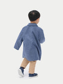 A child wearing a blue cashmere coat with buttons, over a white shirt and beige pants, standing against a white background. #color_deep-slate