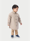 A child wearing a beige cashmere sewn jacket with snap-button design.  #color_beige