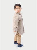 A child wearing a beige cashmere sewn jacket with snap-button design.  #color_beige
