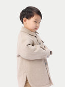 A child wearing a beige cashmere sewn jacket with snap-button design.  #color_beige