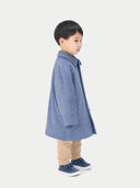 A child wearing a blue cashmere coat with buttons, over a white shirt and beige pants, standing against a white background. #color_deep-slate