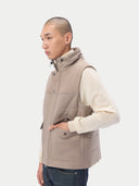 A sleeveless beige cashmere vest with a high collar, front zipper, and two large front flap pockets, shown flat against a light gray background. #color_taupe