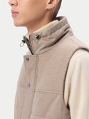 A sleeveless beige cashmere vest with a high collar, front zipper, and two large front flap pockets, shown flat against a light gray background. #color_taupe