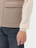 A sleeveless beige cashmere vest with a high collar, front zipper, and two large front flap pockets, shown flat against a light gray background. #color_taupe