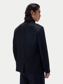 Back view of a man wearing the black cashmere stand-collar jacket against a light gray studio background.