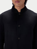 Close-up of the stand collar and dark buttons of the black cashmere jacket.