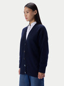 A woman wearing a navy blue button-front cardigan over a white collared shirt and blue jeans, photographed against a clean light gray studio background.