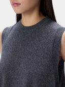 Close-up of a person wearing a dark gray sleeveless knit top against a plain light background.