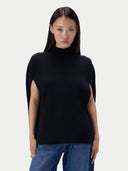 A model wearing a black mock-neck knit top with side cutouts and blue jeans, photographed against a light gray studio background.