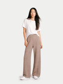 Woman wearing a white t-shirt and brown wide pants on a white background